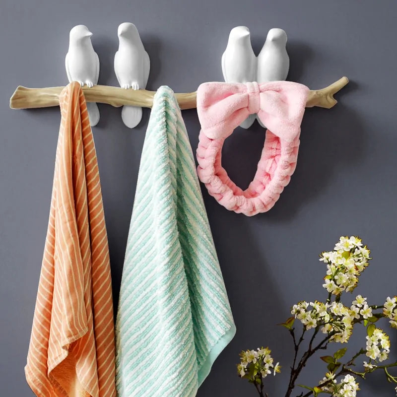 White resin bird wallhanger 3 hook holding two towels and a headband